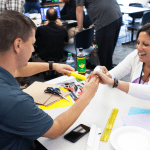 Two educators performing a small arts and crafts project over a table.