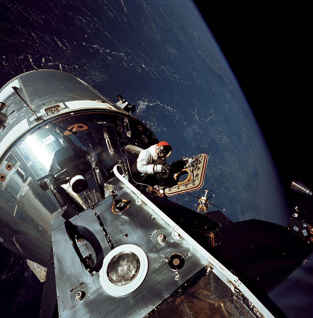 Apollo 9 astronaut Dave Scott stands in the open hatch of the Command Module, nicknamed "Gumdrop," docked to the Lunar Module "Spider" in Earth orb...