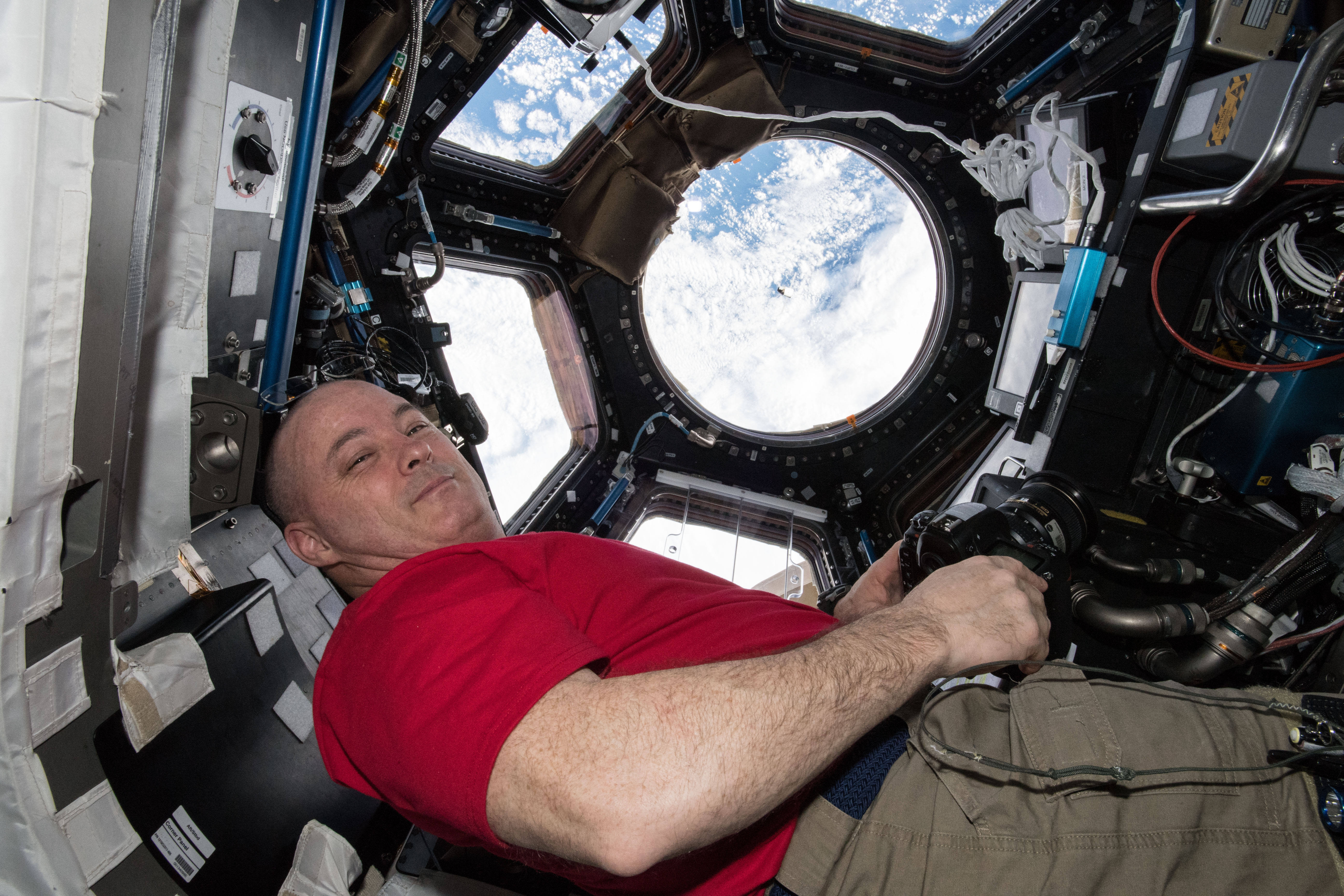 Astronaut Scott Tingle watches the SpaceX Dragon cargo craft arrive from inside the seven-windowed Cupola moments before capturing it with the Cana...